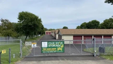 Storage facility entrance with a Five Star Storage sign and red units behind a gate.