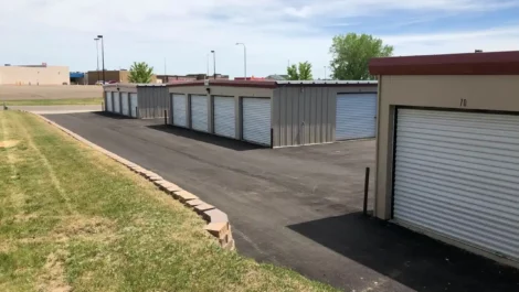 Multiple self-storage units with grass and a paved driveway.
