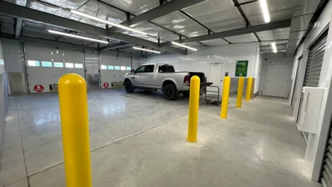 Vehicle storage unit with a truck parked inside and yellow bollards for protection.