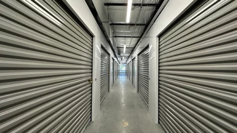 Rows of storage units with roll-up doors along a bright hallway.