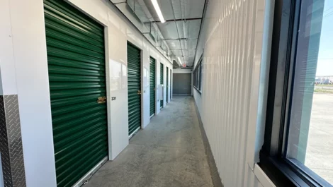 Interior of a storage facility with green storage doors and bright lighting.