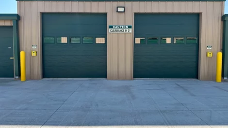Two garage doors at a storage facility with clearance warning and yellow posts.