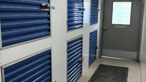 Compact storage units with blue doors and an entrance to larger storage spaces.