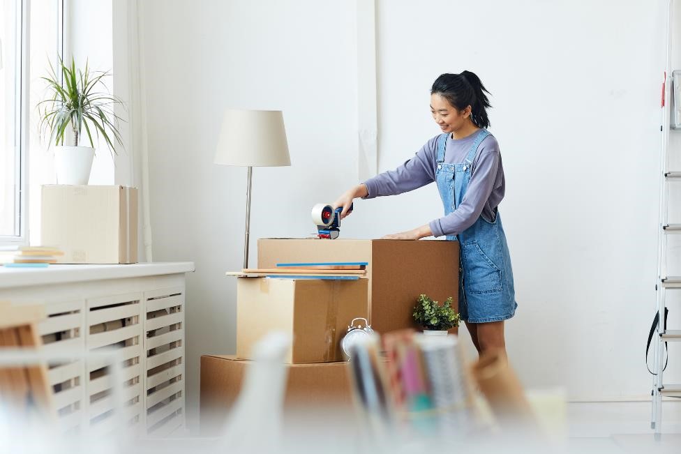 Woman taping a storage box closed.