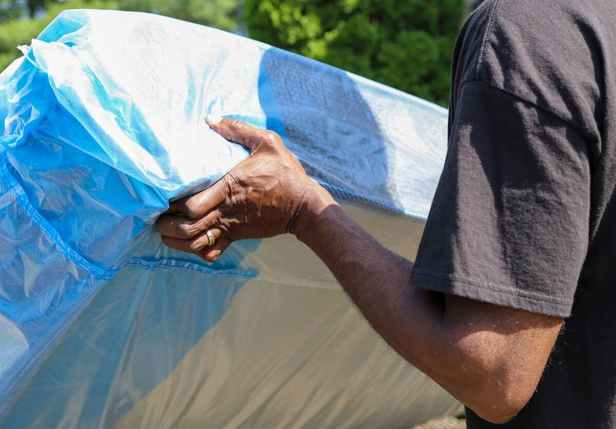 A man moves a mattress wrapped in a protective cover.
