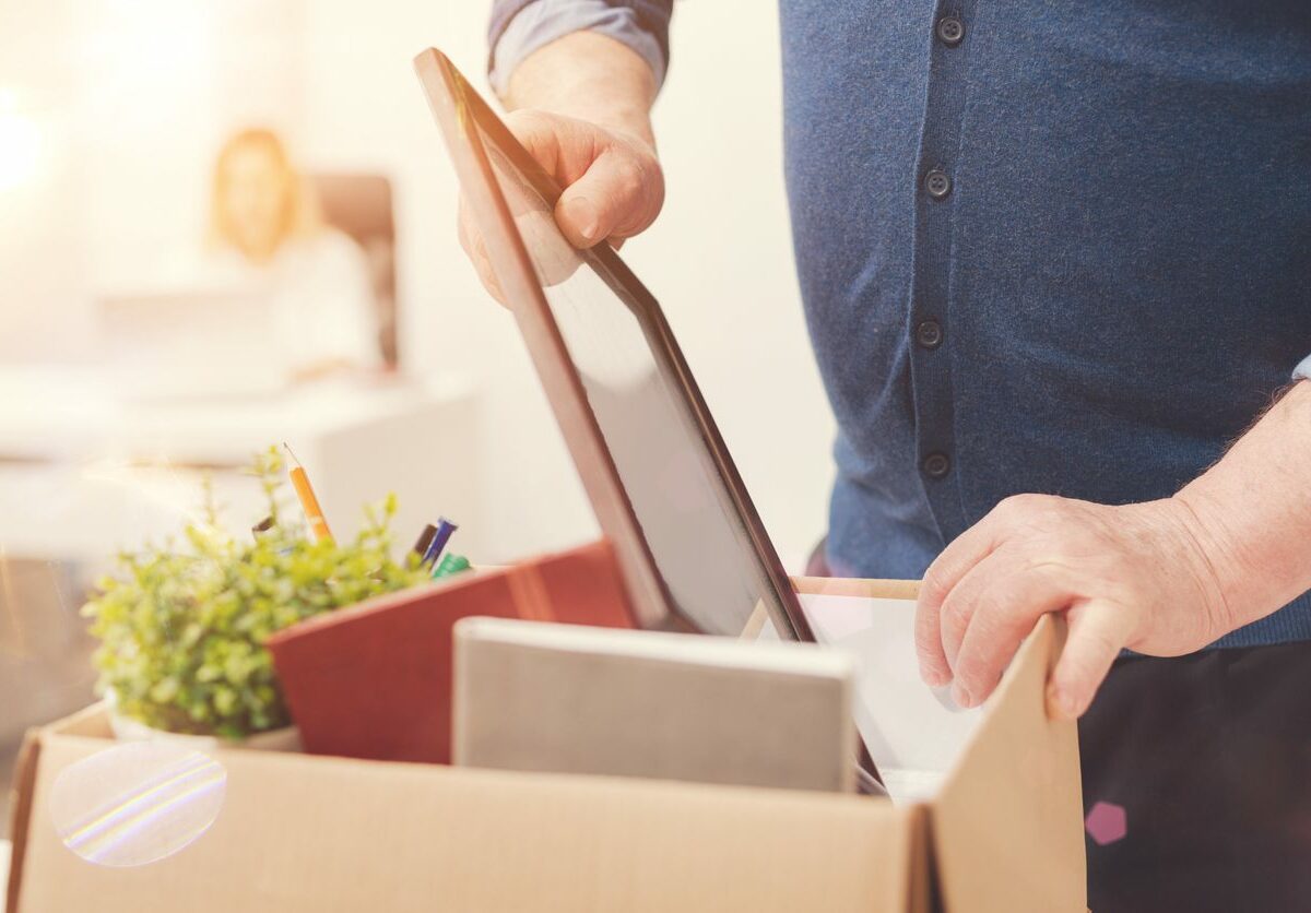 A man packs a picture frame into a box of miscellaneous items