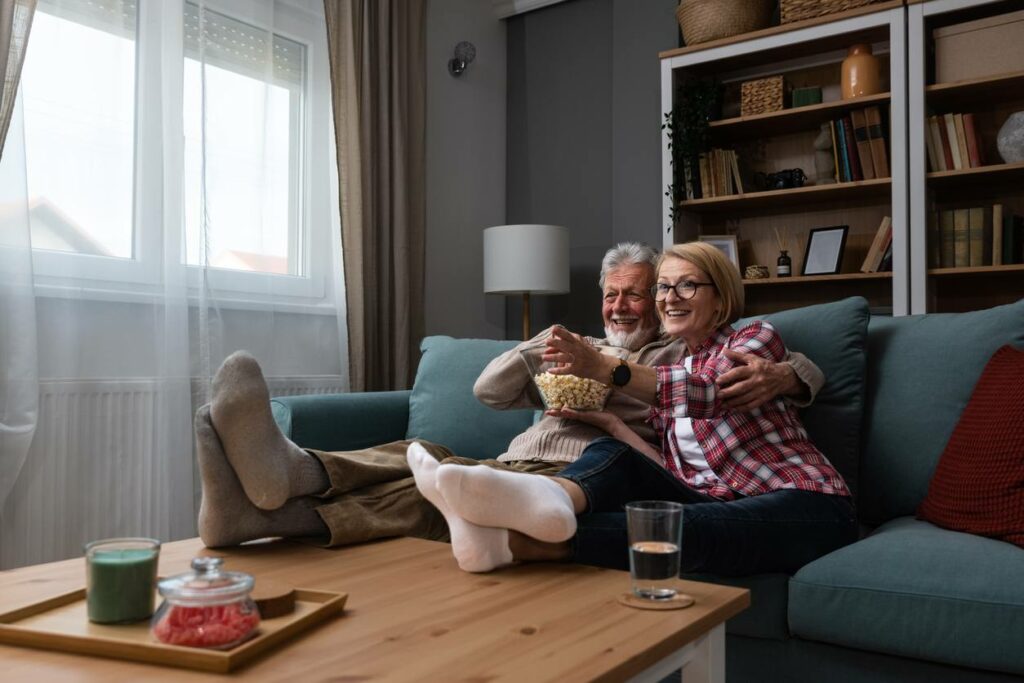 An older couple sits together on the couch, relaxing in their decluttered home.