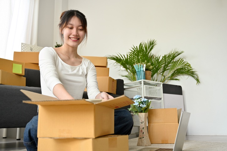 A woman unpacks her belongings out of boxes as she moves into a new apartment.