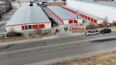 Wide view of 14th Street Self Storage with red units and cars on the road outside.