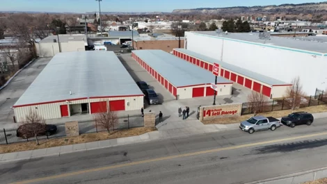 Wide view of 14th Street Self Storage with red units and cars on the road outside.