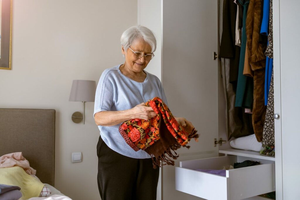 Woman smiling as she places blanket inside an organized closet.