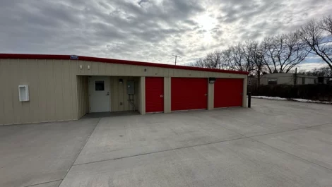 Self-storage units with red doors and a main entrance to the building.