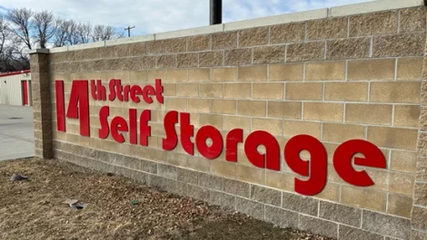 14th Street Self Storage sign on a brick wall marking the entrance to the facility.