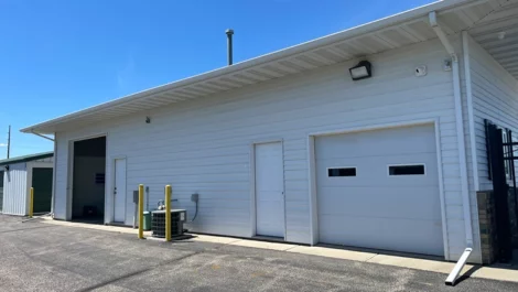 Storage facility with a white building including a garage door and security posts.