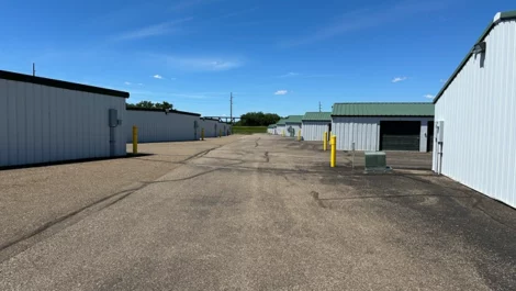 Storage units on either side of an accessible road with yellow bollards.