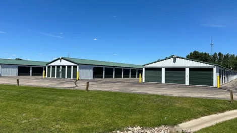 Spacious storage facility with green-roofed units and open parking space.