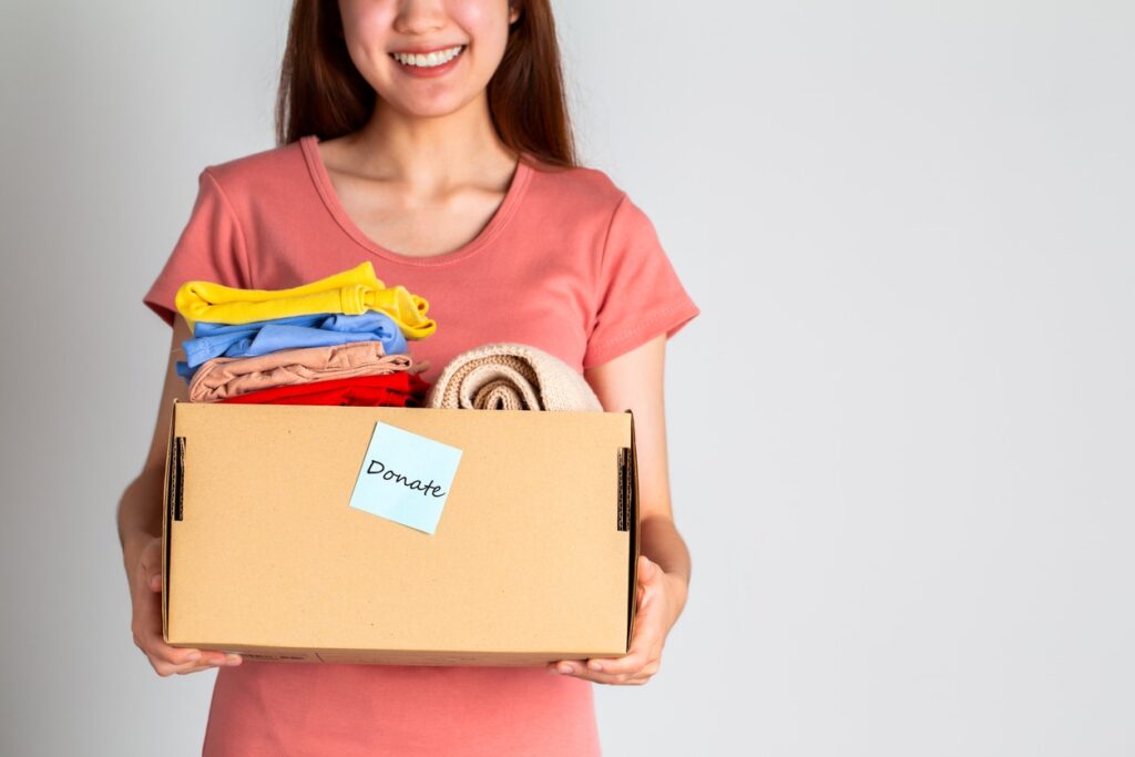 A woman holding a cardboard box full of items to be donated.