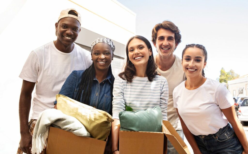 A group of students smiling for a portrait to commemorate moving into their college dorm.