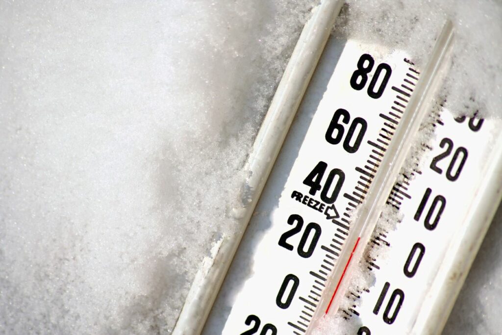 A black and white thermometer partially buried in the snow.