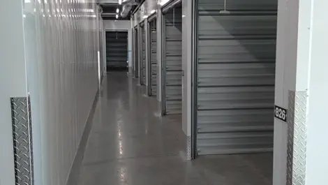 Neat and organized storage unit hallway with metal doors and clean floors.