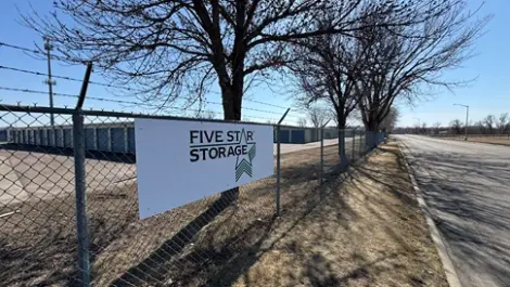 Storage facility with a Five Star Storage sign on a fence and units in the distance.