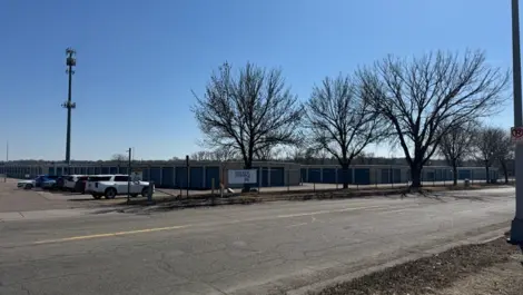 Storage units with car storage spaces and vehicles parked along the road.