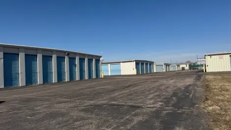 Storage units lined up along a wide paved path in an open area.