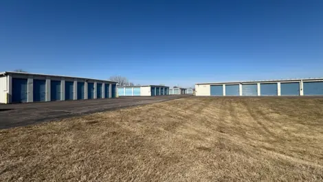 Storage facility with multiple units along a paved path and open land.