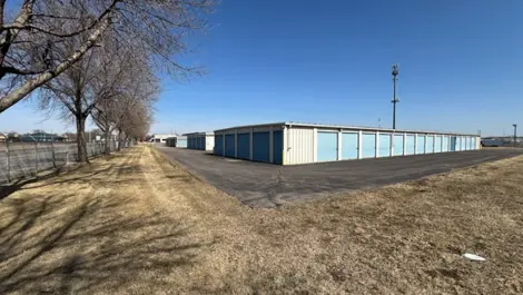 Storage facility with units alongside a paved path and grassy area.