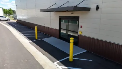 Exterior of a storage facility with a sliding door and marked parking spaces.