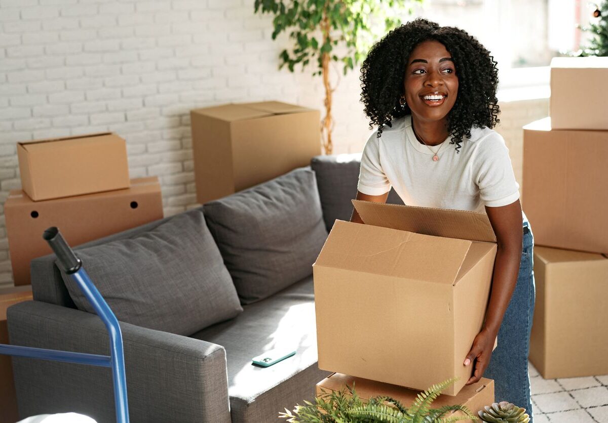 A young woman lifts a cardboard box while moving to a new apartment.