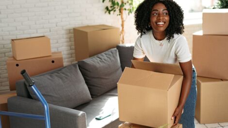 A young woman lifts a cardboard box while moving to a new apartment.