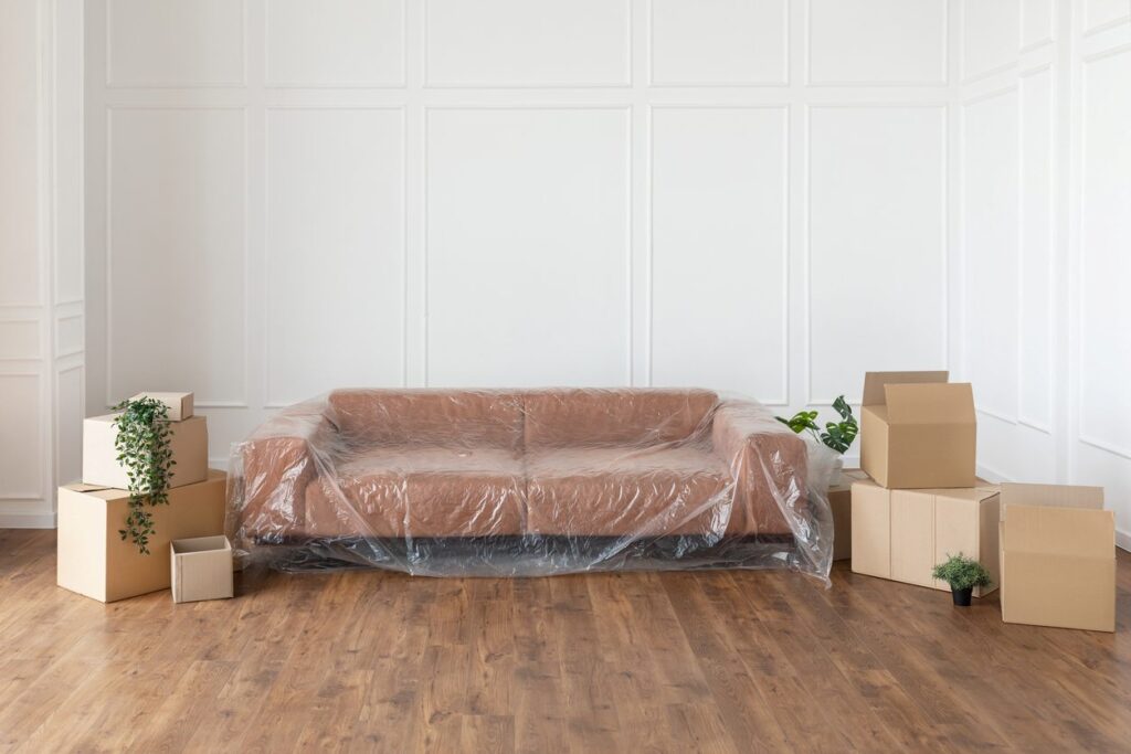 A brown couch surrounded by several brown boxes on the floor.