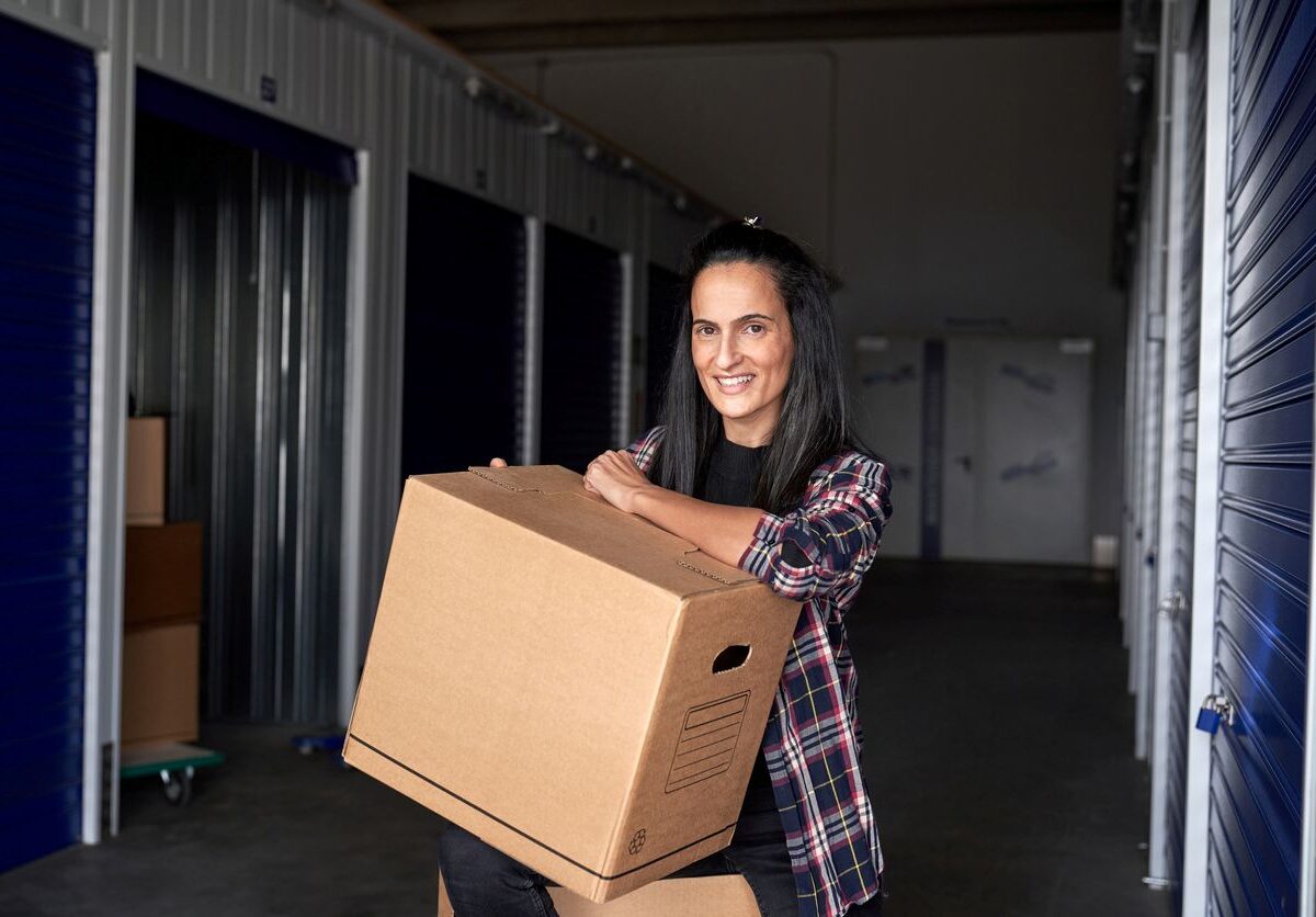 A woman holding a cardboard box, before dropping it off at her storage unit.